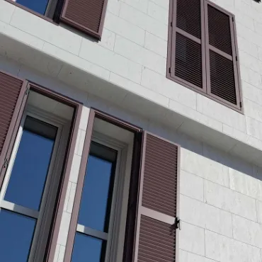 Celosías fijas de aluminio instaladas en ventanas de edificio con fachada blanca