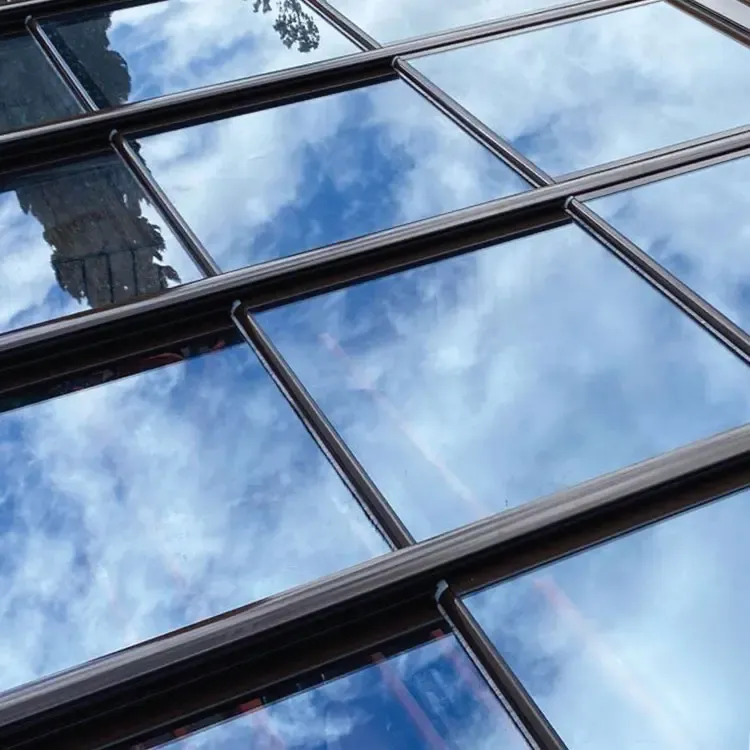 Techo móvil de cristal con perfilería negra y reflejo del cielo