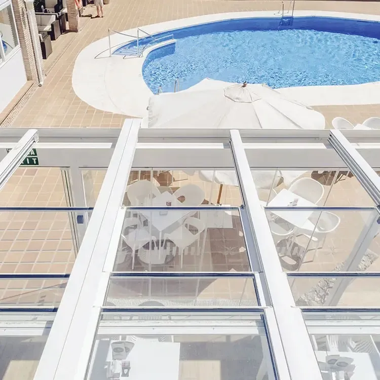 Techo móvil panorámico de cristal con estructura blanca junto a piscina exterior