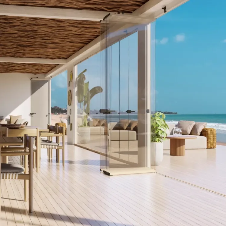Cortinas de cristal abatibles recogidas en un extremo de una terraza abierta al mar