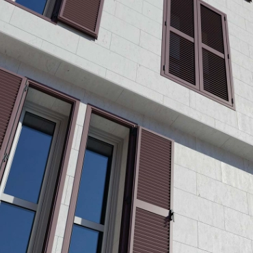 Celosías fijas de aluminio instaladas en ventanas de edificio con fachada blanca